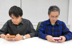 新旧のゲーム＆ウオッチを試遊する、龍田さん（左）と早川さん（右）