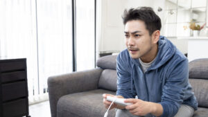 家庭用ゲームを遊ぶ大人の男性のイメージ（画像：写真AC）